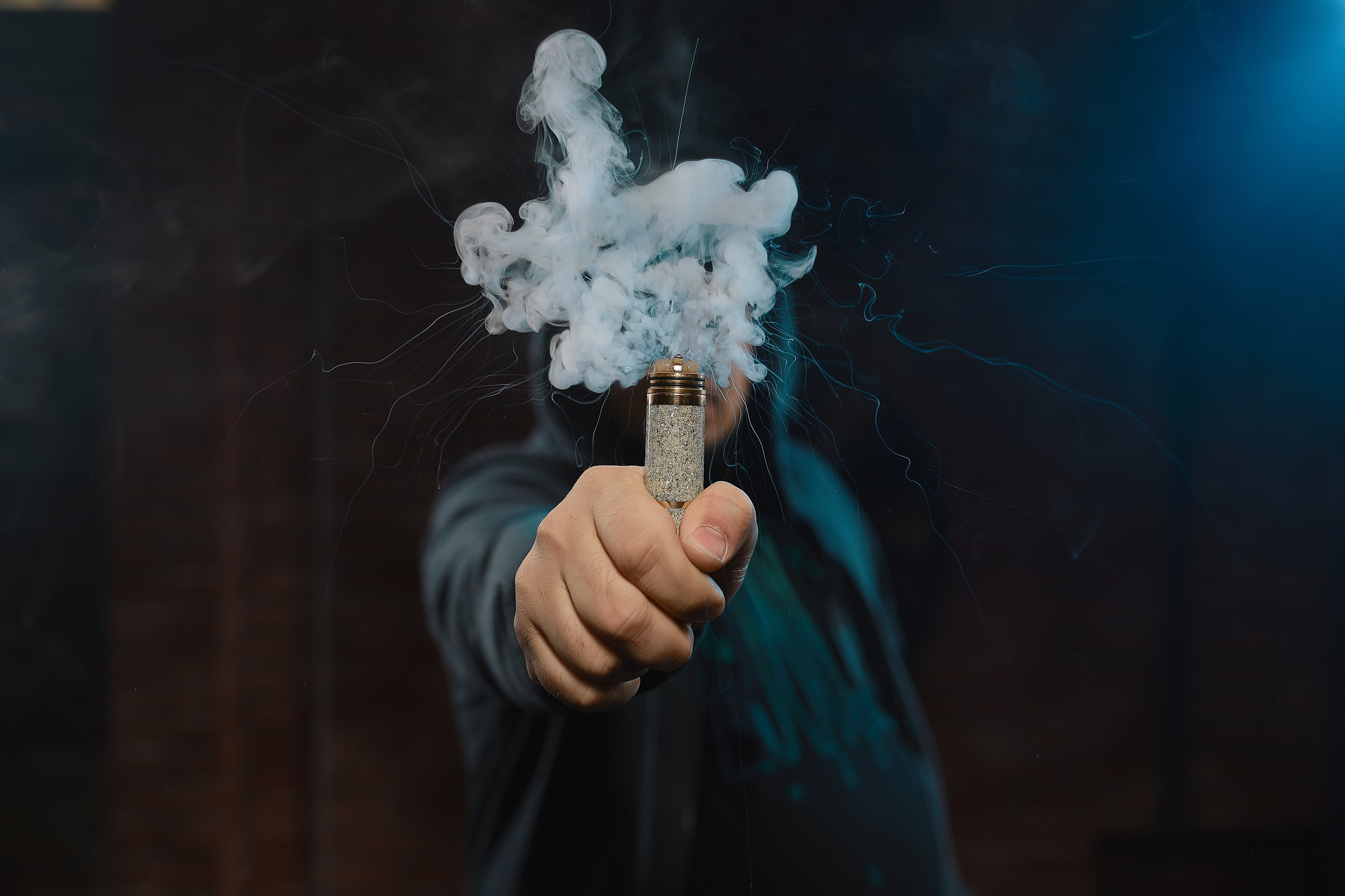 A person holding a vape in front of them with vape smoke covering their face