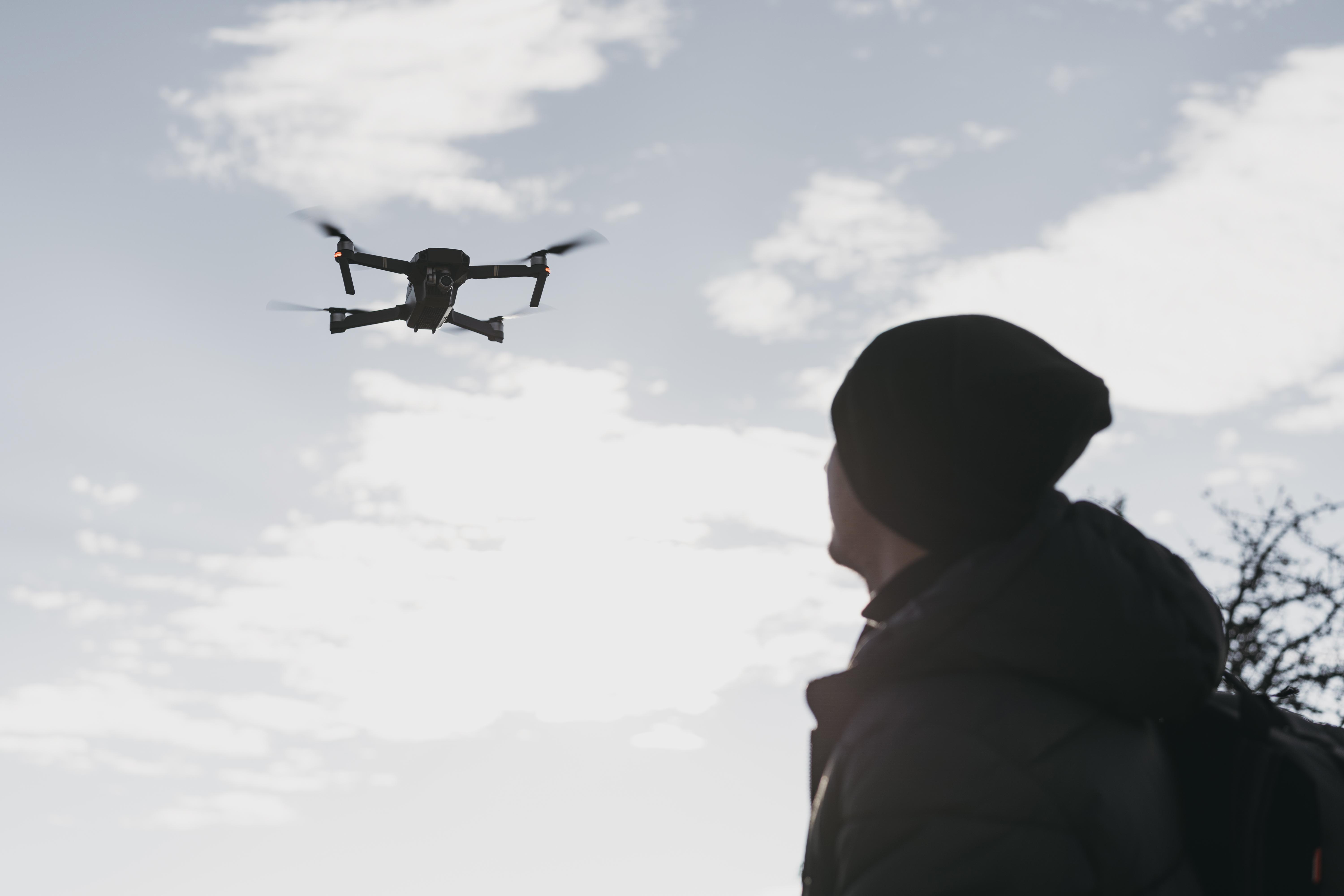 Someone looking up in the sky at a drone hoovering above them